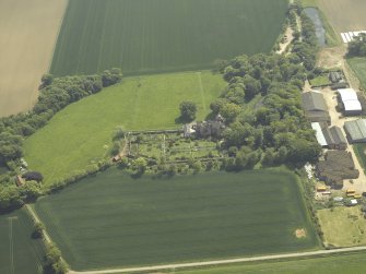 Oblique aerial view centred on the remains of the castle, stable and walled garden, taken from the NW.