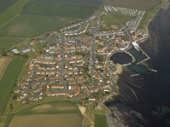 General oblique aerial view of the village centred on the harbour with the church and the burial-ground adjacent, taken from the SW.