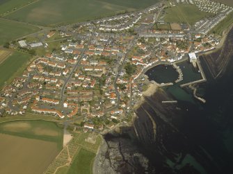 General oblique aerial view of the village centred on the harbour with the church and the burial-ground adjacent, taken from the SSW.