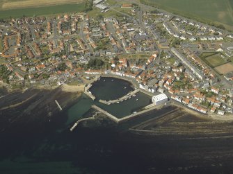 Oblique aerial view of the village centred on the harbour, taken from the SE.