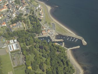 Oblique aerial view centred on the harbour with the monastery, garden, church, churchyard and burial ground adjacent, taken from the W.