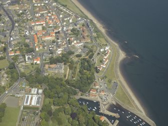 Oblique aerial view centred on the house, monastery and gardens with the church, burial ground and harbour adjacent, taken from the WSW.