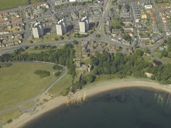 Oblique aerial view centred on the remains of the castle and the graveyard with the flats adjacent, taken from the SSE.