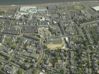 General oblique aerial view centred on the clock tower and town house with the church adjacent, taken from the NW.