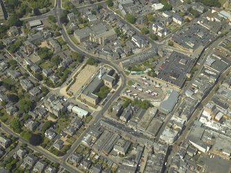 General oblique aerial view centred on the clock tower and town house with the church adjacent, taken from the S.