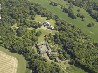 Oblique aerial view centred on the country house and stable block, taken from the NW.