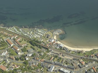 Oblique aerial view centred on the church, burial ground and harbour, taken from the WNW.