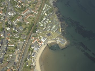 Oblique aerial view centred on the church, burial ground and harbour, taken from the SW.