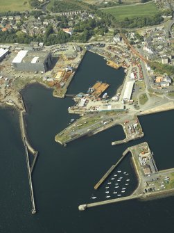 Oblique aerial view of the harbour centred on the outer harbour, breakwaters, dock and engine house, taken from the SSE.