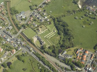 Oblique aerial view centred on the remains of the castle, dovecot and walled garden and the church and burial-ground, taken from the W.