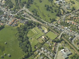 Oblique aerial view centred on the remains of the castle, dovecot and walled garden and the church and burial-ground, taken from the ESE.