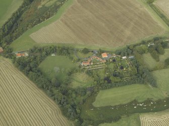 Oblique aerial view centred on the country house, cottage and walled garden, taken from the SSW.