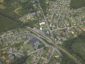 Oblique aerial view of the village centred on the railway station and school, taken from the SW.