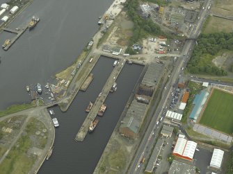 Oblique aerial view centred on the burnt out sugar warehouse and the docks, taken from the WNW.