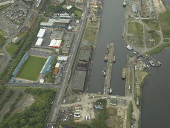 Oblique aerial view centred on the burnt out sugar warehouse and the docks, taken from the ESE.