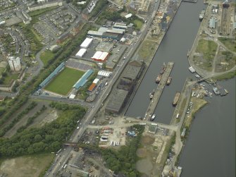 Oblique aerial view centred on the burnt out sugar warehouse and the docks, taken from the E.