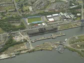 Oblique aerial view centred on the burnt out sugar warehouse and the docks, taken from the NE.