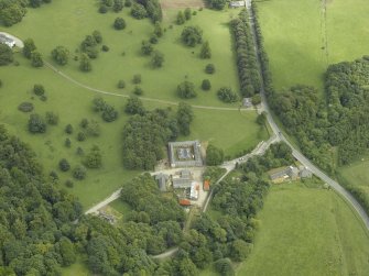 Oblique aerial view centred on the stable block, gate-lodge and road bridge, taken from the WNW.