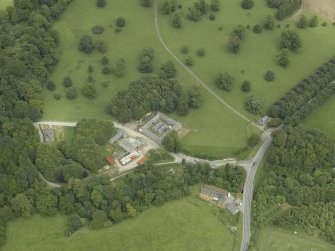 Oblique aerial view centred on the stable block, gate-lodge and road bridge, taken from the WSW.