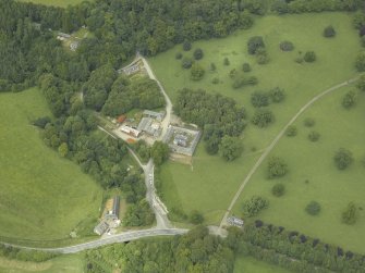 Oblique aerial view centred on the stable block, gate-lodge and road bridge, taken from the S.