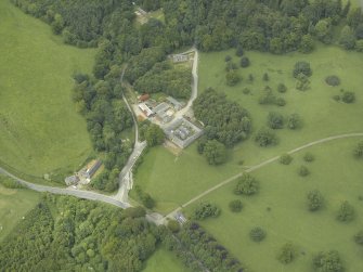 Oblique aerial view centred on the stable block, gate-lodge and road bridge, taken from the SE.