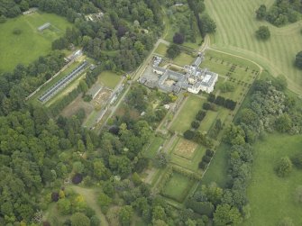 Oblique aerial view centred on the country house, walled garden, gardens and terraces, taken from the WSW.