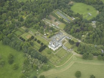 Oblique aerial view centred on the country house, walled garden, gardens and terraces, taken from the SE.