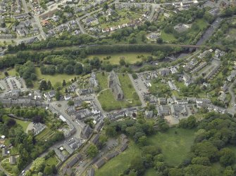 Oblique aerial view of the town centred on the cathedral, chapel, burial-ground and hall with the railway viaduct adjacent, taken from the E.