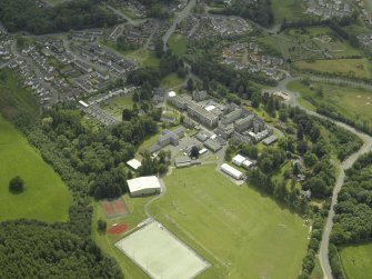 Oblique aerial view centred on the school, church, hospital and house, taken from the NE.