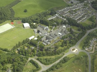 Oblique aerial view centred on the school, church, hospital and house, taken from the WNW.