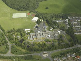 Oblique aerial view centred on the school, church, hospital and house, taken from the W.