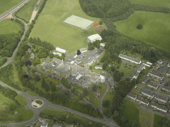 Oblique aerial view centred on the school, church, hospital and house, taken from the SW.