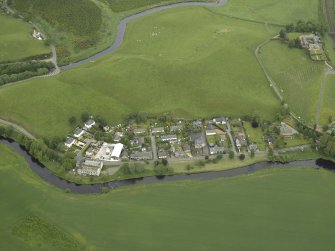 Oblique aerial view of the village centred on the woollen mill, taken from the WSW.