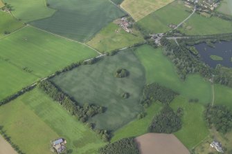 Oblique aerial view centred on the cropmarks of the pits and rig with the farmhouse and farmsteading adjacent, taken from the S.