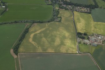 Oblique aerial view centred on the cropmarks of the cursus with the cropmarks of the possible settlement and the farmhouse, farm buildings and dovecot adjacent, taken from the ENE.