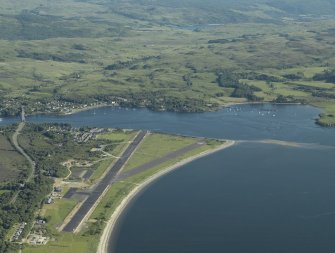 General oblique aerial view centred on the airfield during resurfacing of the runway with the village, road bridge and railway bridge adjacent, taken from the NNW.