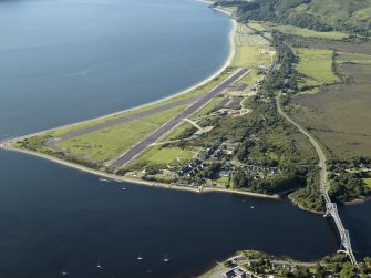 General oblique aerial view centred on the airfield during resurfacing of the runway with the village, road bridge and railway bridge adjacent, taken from the S.