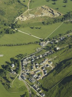 General oblique aerial view of the village, centred on the church, churchyard, burial ground and museum with the tower-house and quarry adjacent, taken from the SE.