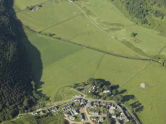 Oblique aerial view centred on the church, churchyard, burial-ground and museum with the remains of the cairns adjacent, taken from the NE.