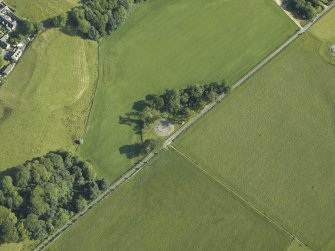 Oblique aerial view centred on the remains of the stone circles with the remains of the standing stone adjacent, taken from the SE.