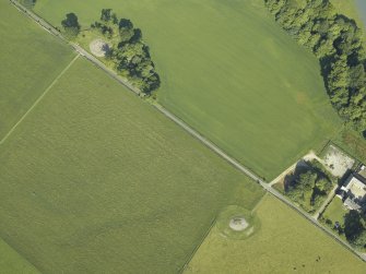 Oblique aerial view centred on the remains of the chambered cairn with the remains of the standing stone and stone circles and the farmstead adjacent, taken from the ESE.