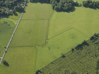 Oblique aerial view centred on the remains of the standing stones, henge and barrow, taken from the NW.
