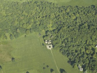 Oblique aerial view centred on the ruins of the country house with the church adjacent, taken from the ESE.