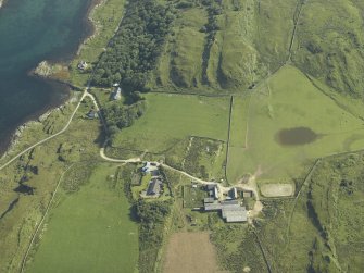 Oblique aerial view centred on the farmhouses, farmsteading and cottages, taken from the SSW.
