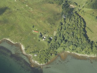 Oblique aerial view centred on the remains of the chapel and burial-ground and the cottages, taken from the NE.