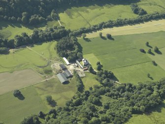 Oblique aerial view centred on the country house with the remains of the cairn adjacent, taken from the NNW.