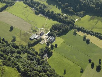 Oblique aerial view centred on the country house with the remains of the cairn adjacent, taken from the WNW.