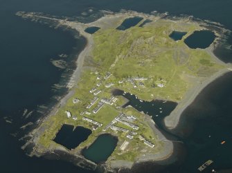 Oblique aerial view of the island, centred on the remains of the quarries and the harbour, taken from the E.