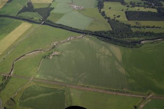 Oblique aerial view centred on the cropmarks of the rig and pits with the farmhouse and farmsteading adjacent, taken from the SE.