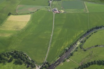 Oblique aerial view centred on the cropmarks of the rig with the farmhouse and farmsteading adjacent, taken from the WSW.